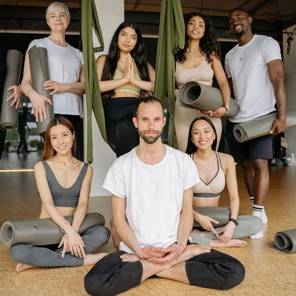A diverse group of people smiling during a yoga class.