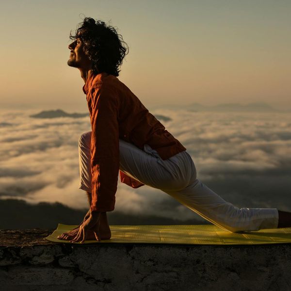 Silhouette of a person in a yoga balance pose at sunrise.